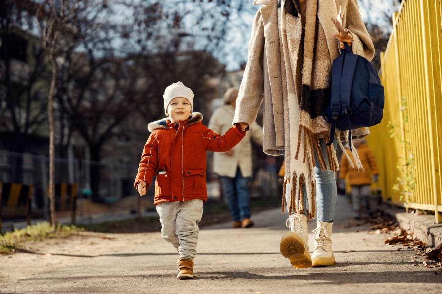 A parent walking hand-in-hand with their toddler outdoors, illustrating a comfortable transition into a licensed child care program in Mississauga.